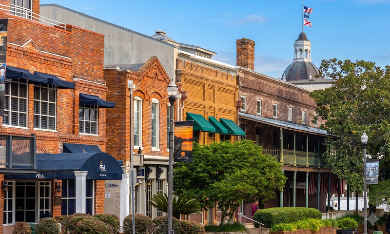 Downtown Tallahassee brick storefronts and street banners under a blue sky.